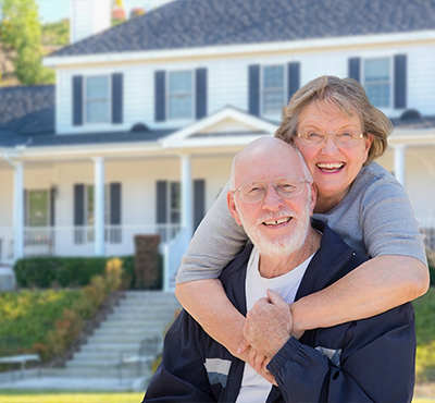 Happy Senior Couple in Front of House.