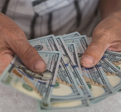 Close-up of an elderly man's hands holding American dollar bills.