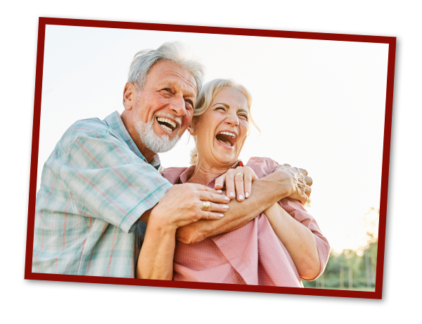 Senior couple together hugging and smiling.