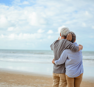 A senior couple hugging each other at the beach in the morning.